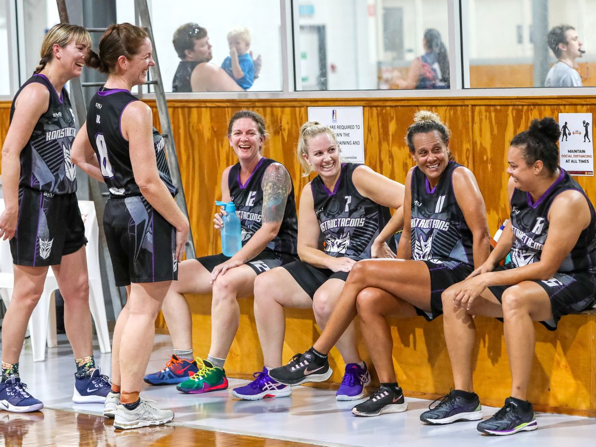 Women's basketball team sitting on the sideline laughing